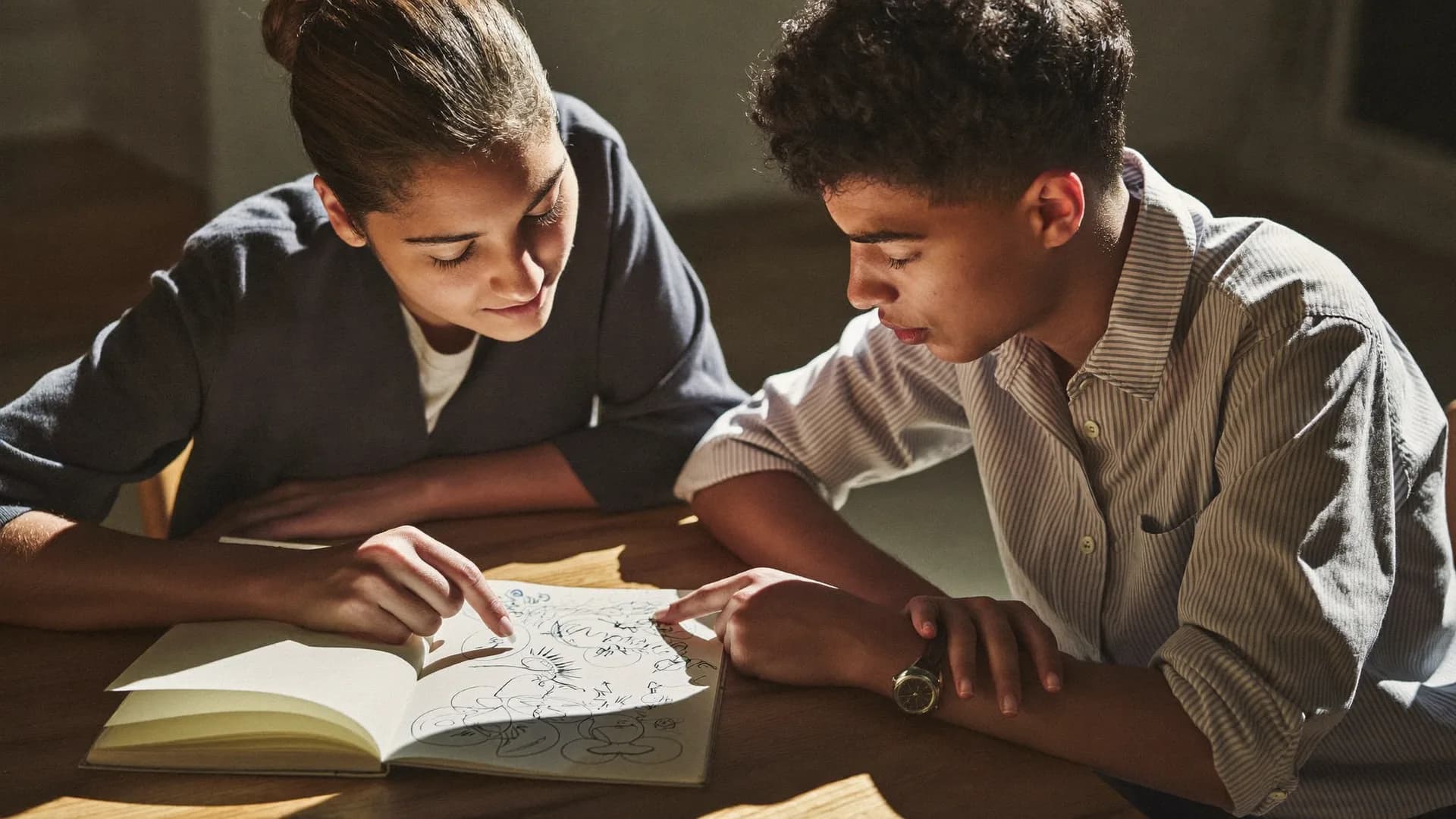 Mentora e estudante analisando juntos um plano desenhado num caderno